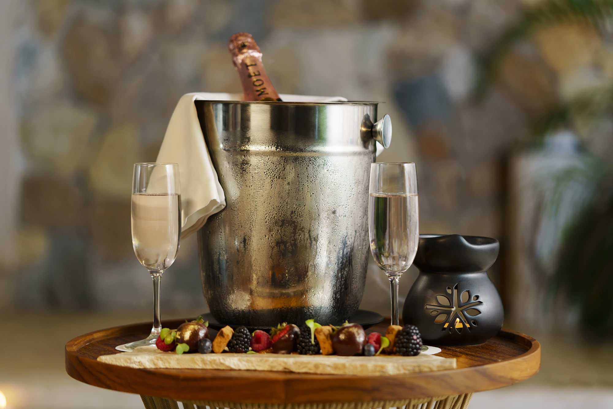 Champagne in ice bucket, flanked by glasses and candleholder on table at Hacienda Xcanatun, Angsana Heritage Collection.
